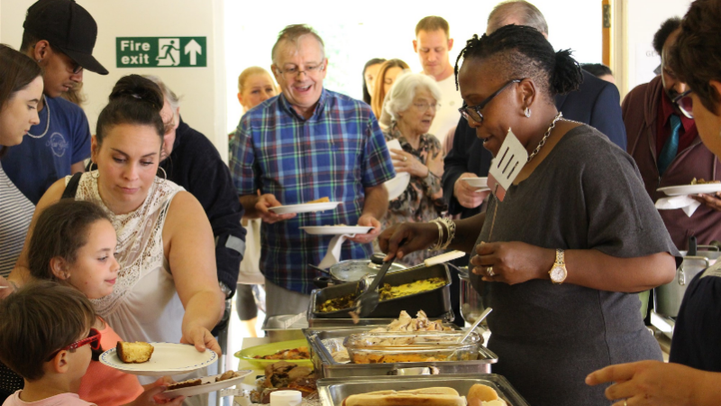 A group of people gathering around a food buffet for lunch