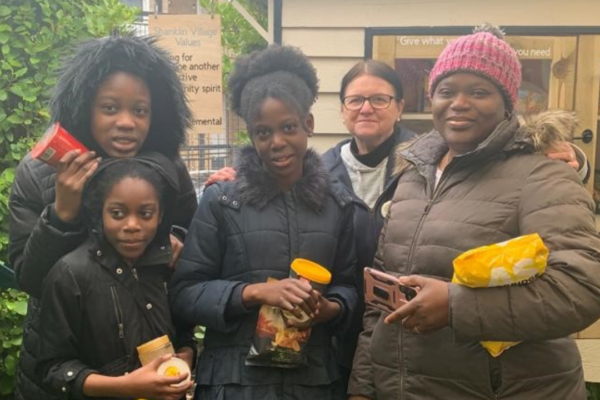 Local family standing in front of the community cupboard