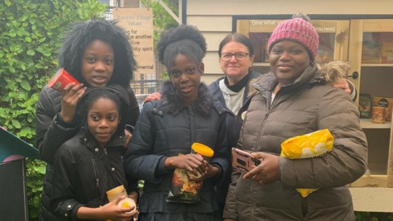 Local family standing in front of the community cupboard